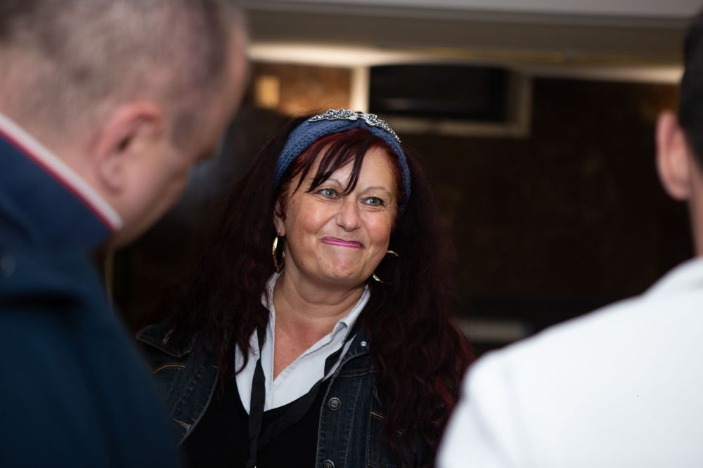 Woman with red hair and blue headband smiling at an indoor film festival event.