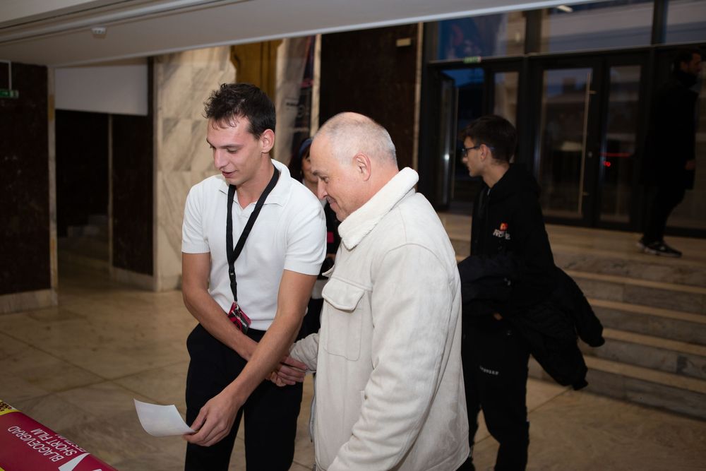 Two men reviewing documents in a marble lobby at a film festival.
