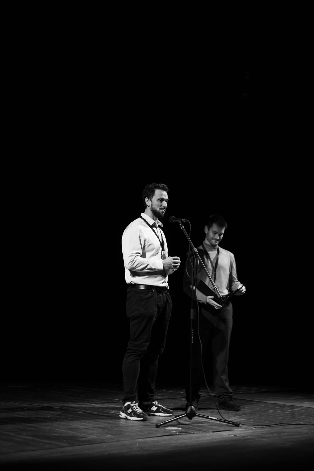 Two men presenting on stage at a film festival in black and white photography.