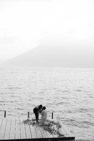 A minimalist black and white photo series shows someone crouching on a wooden dock by a misty lake.