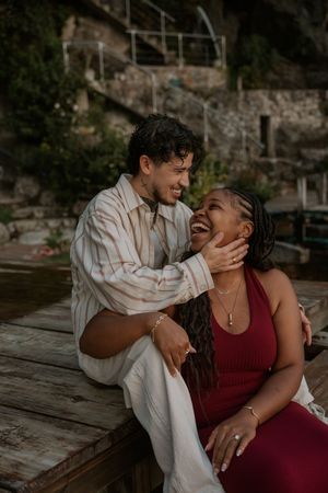 A couple shares intimate laughter and playful moments on a rustic wooden deck.