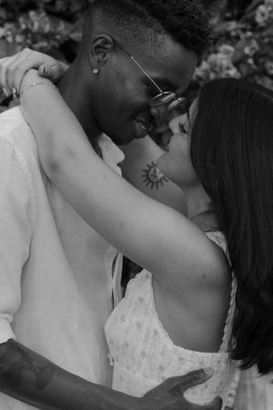 A romantic black and white portrait of a couple in an intimate embrace outdoors.