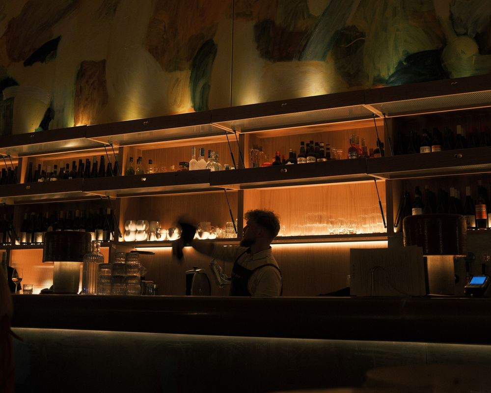 Dimly lit bar interior with warm ambient lighting and bottles displayed on shelves.