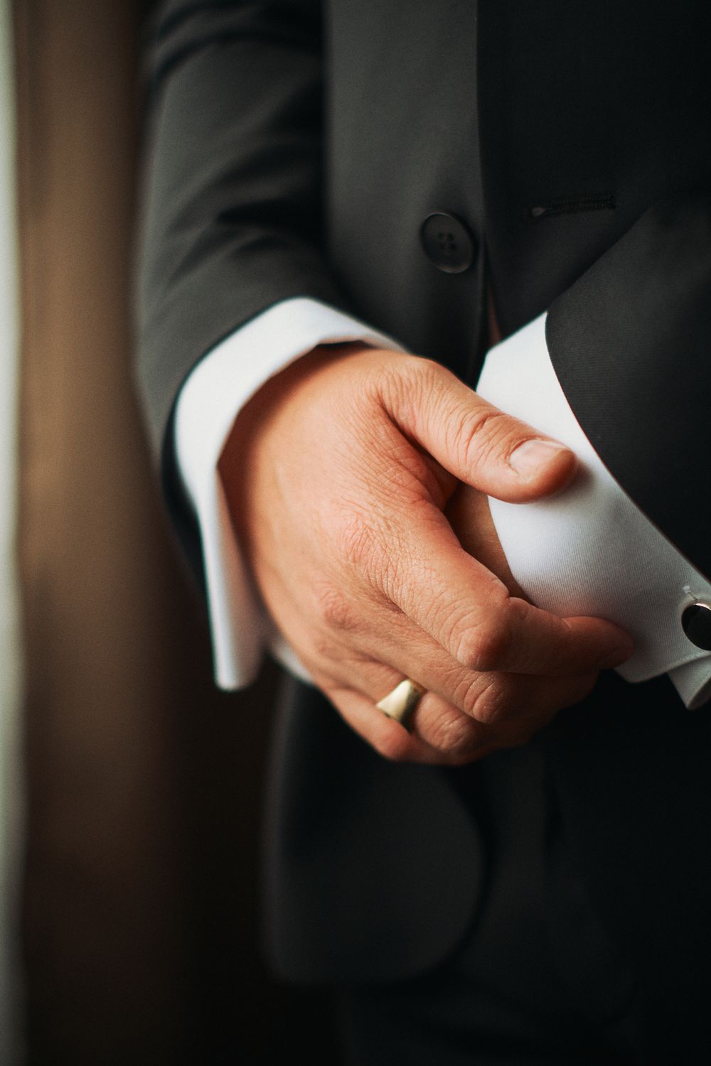 Close-up view of hands wearing formal white cuffs and black suit sleeves arranged in a row.
