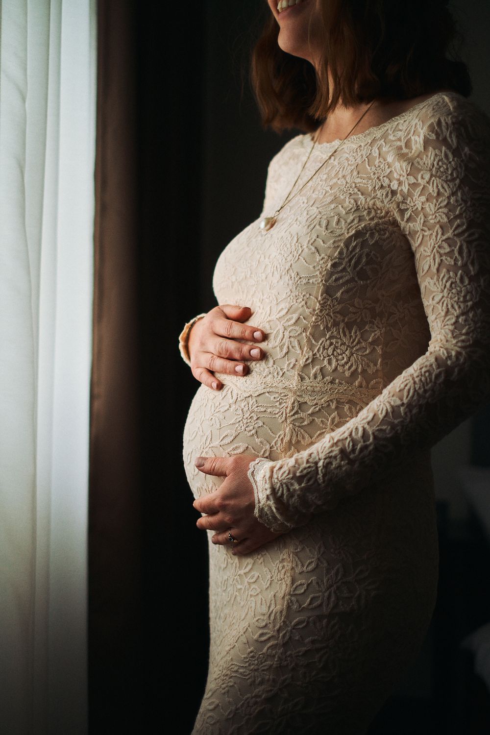 A series of artistic maternity photos showing a pregnant woman in white lace dress against dark background.