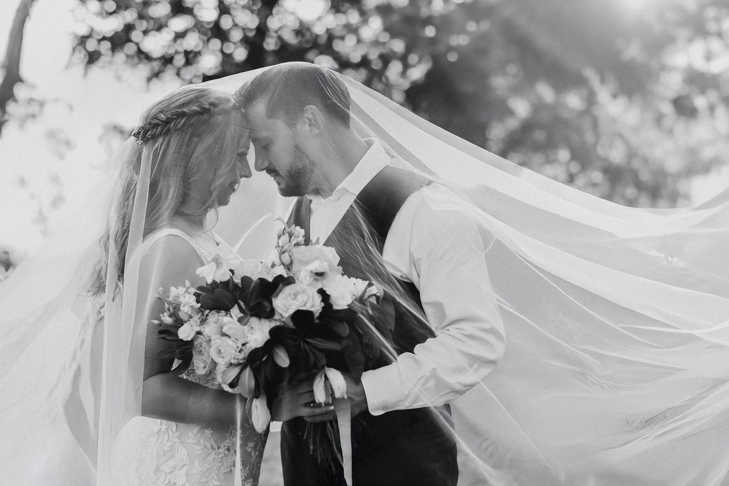 Editorial spring wedding portrait of the bride and groom surrounded by natural greenery and soft light.