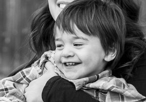 Young boy smiling in mothers arms.