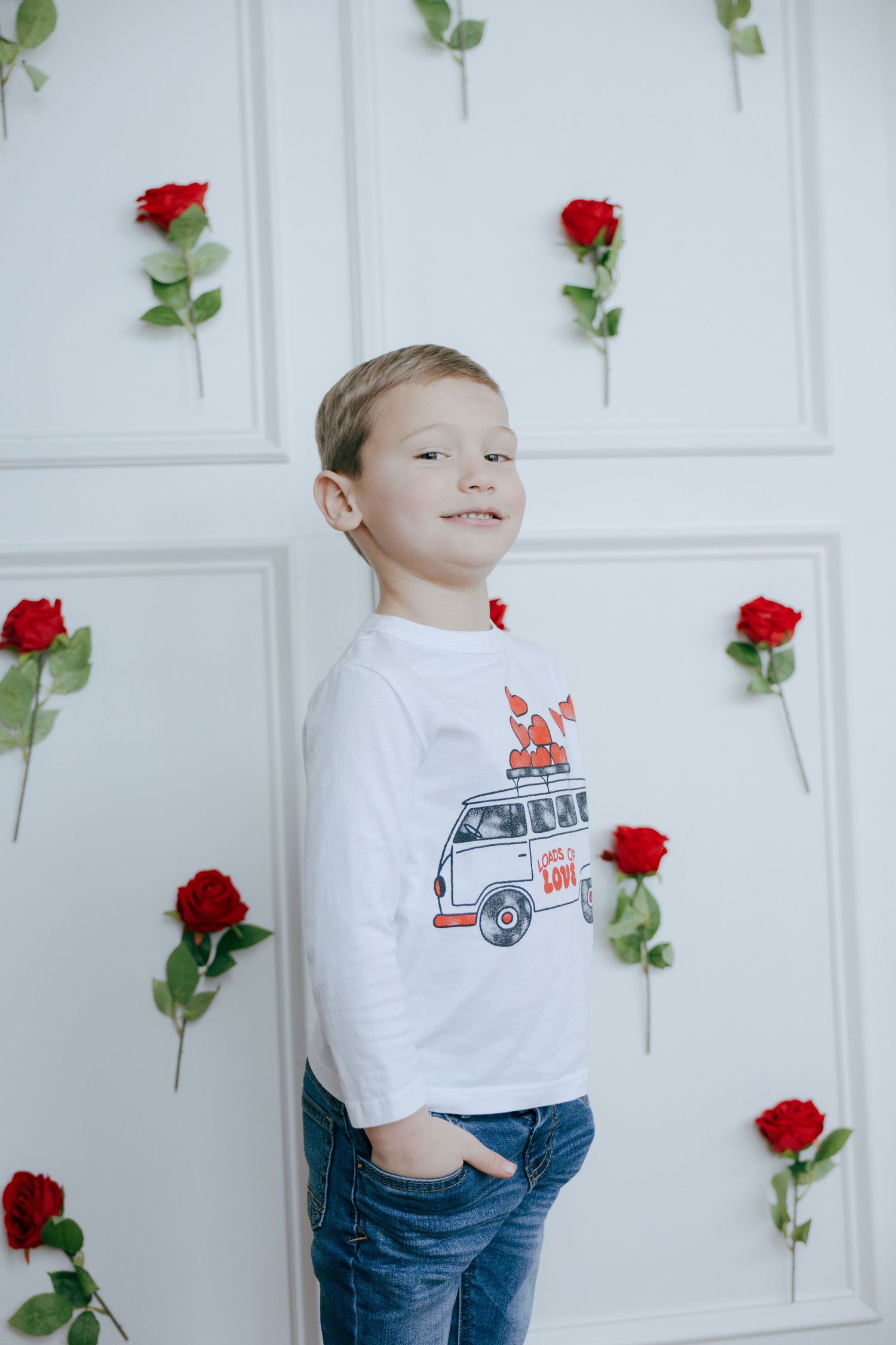 A series of photos showing a child in a white t-shirt and jeans posing against a white wall decorated with red roses.
