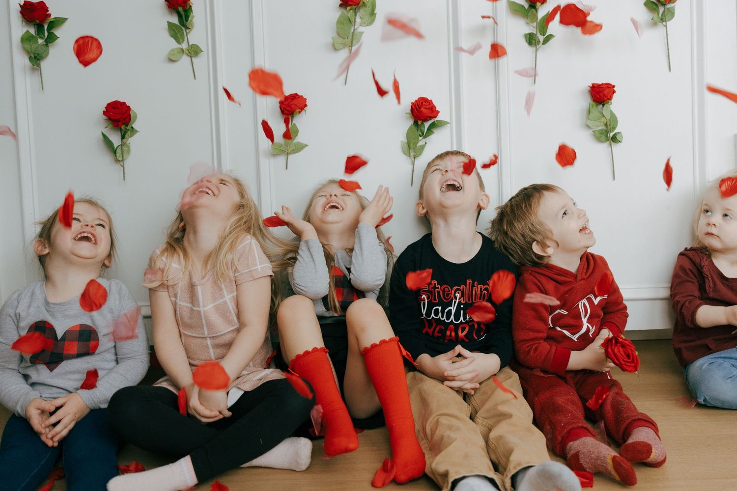 A sequence of photos showing rose petals falling while people in red and black clothing pose on the floor.