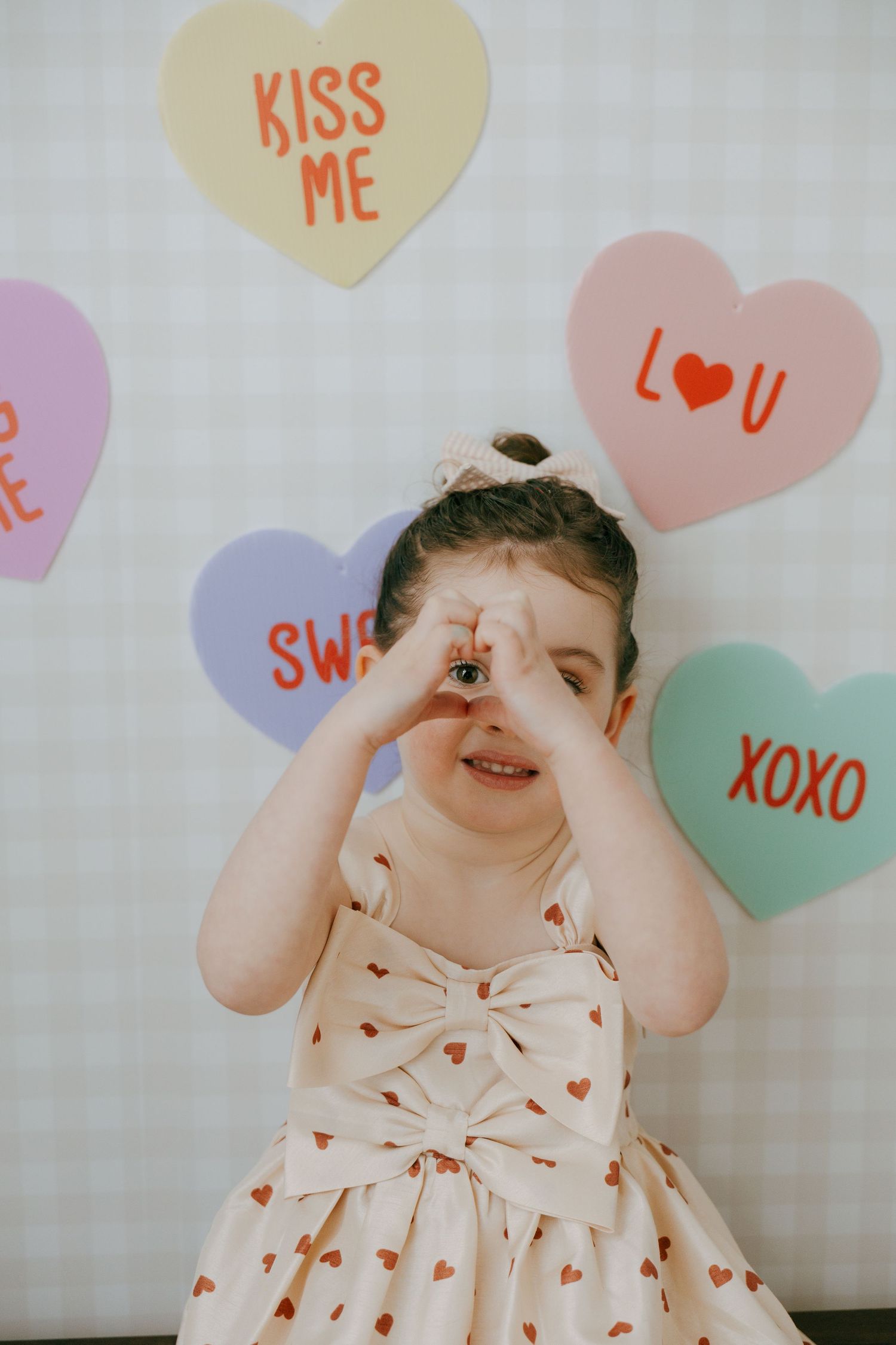 A playful scene with candy heart decorations reading 'Kiss Me', 'Love U', and 'XOXO' against a light background.