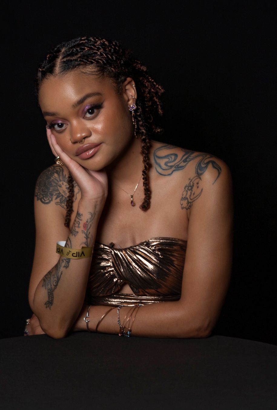 Artistic portrait series showing a model in a metallic bronze top against a dark background with visible tattoos.