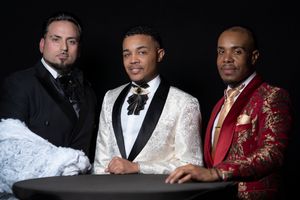 Group photo of men in formal attire including white and red tuxedos posing together.