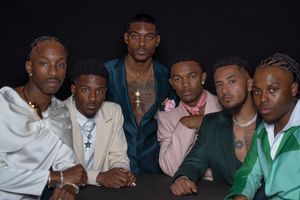 Group portrait of people in casual attire against dark backdrop.