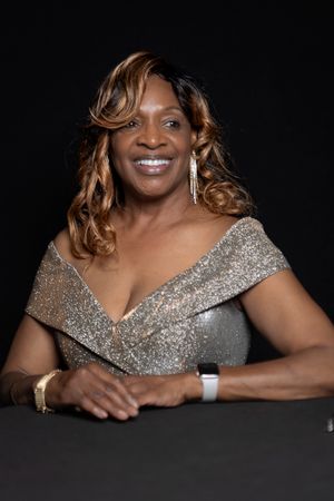 Elegant portrait featuring a person in a sparkly silver evening gown with curled hair against dark backdrop.