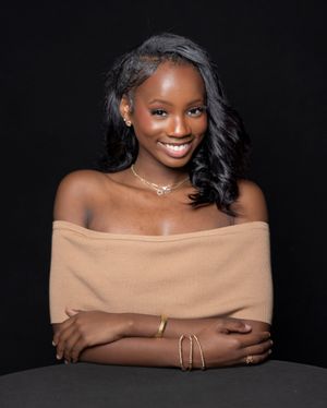 Elegant portrait series featuring off-shoulder tan wrap with jewelry against dark backdrop.