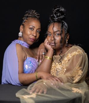 Two people in purple and gold formal wear embracing for portrait.