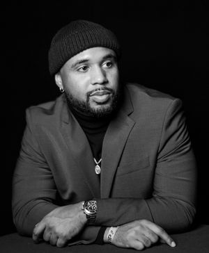Portrait series of person in dark suit and beanie against black background showing different expressions.