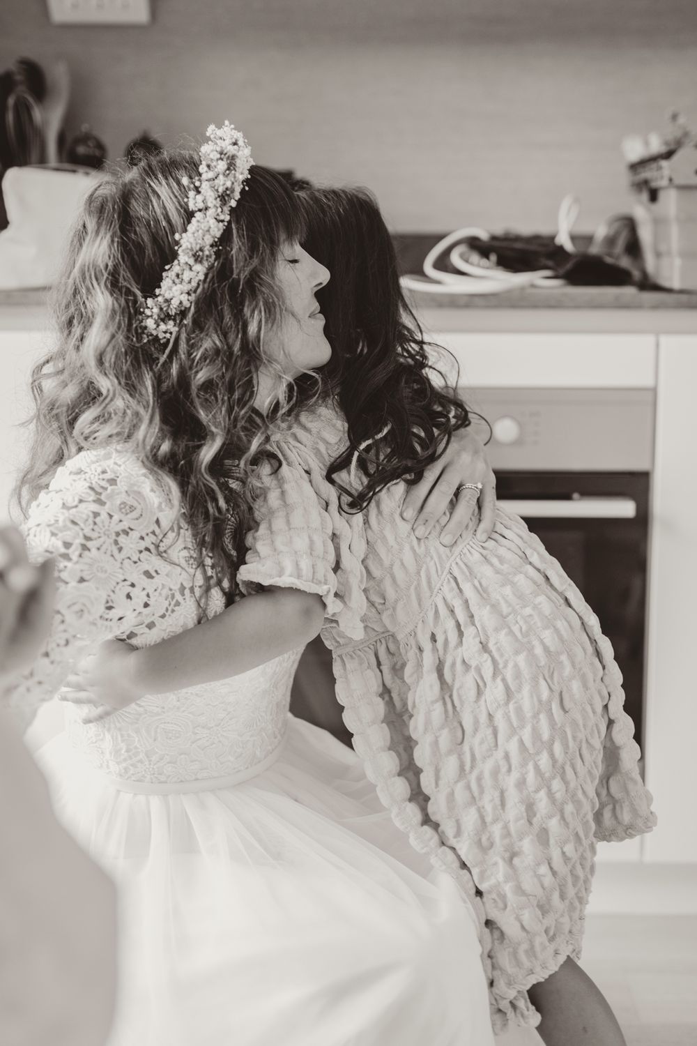 A tender moment captured in black and white as a bride embraces a loved one during wedding preparations.