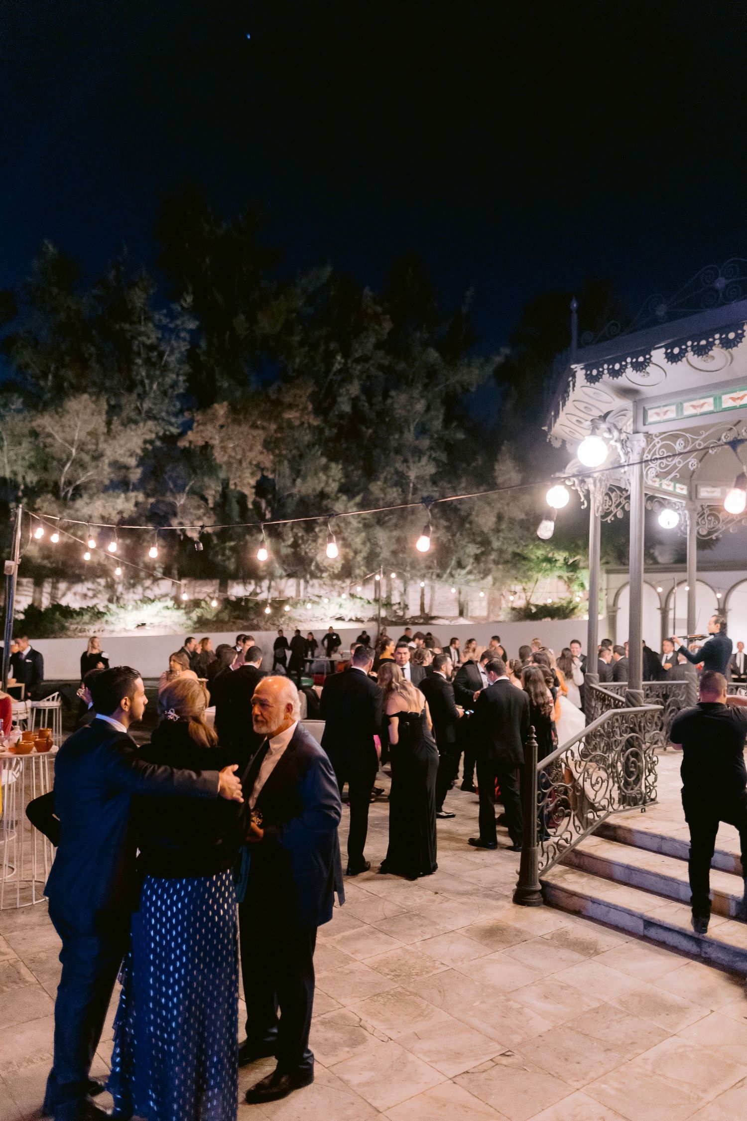 Bride and groom share a romantic dance together in an elegant ballroom with chandelier lighting and white floral decor.