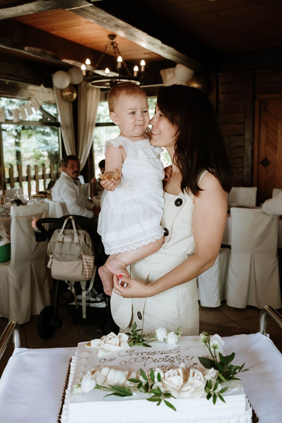 A tender moment shared during a wedding reception in a rustic venue with white decor and floral arrangements.