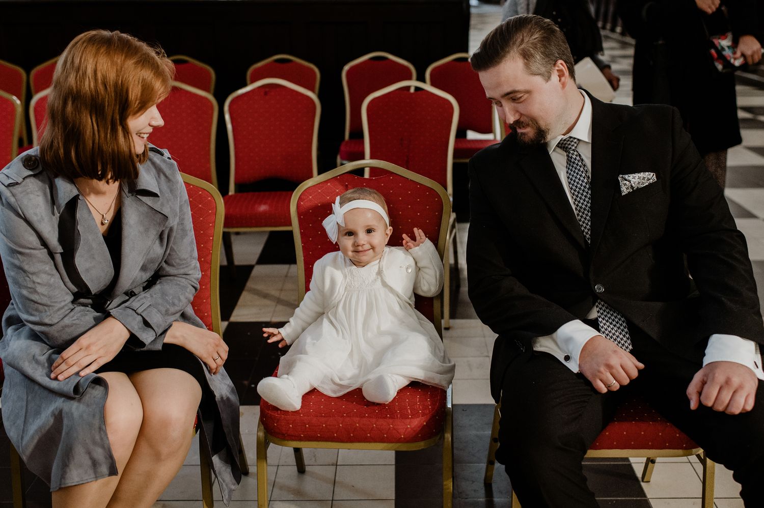 A series of black and white photos showing intimate wedding moments with couples and guests sitting in red chairs.