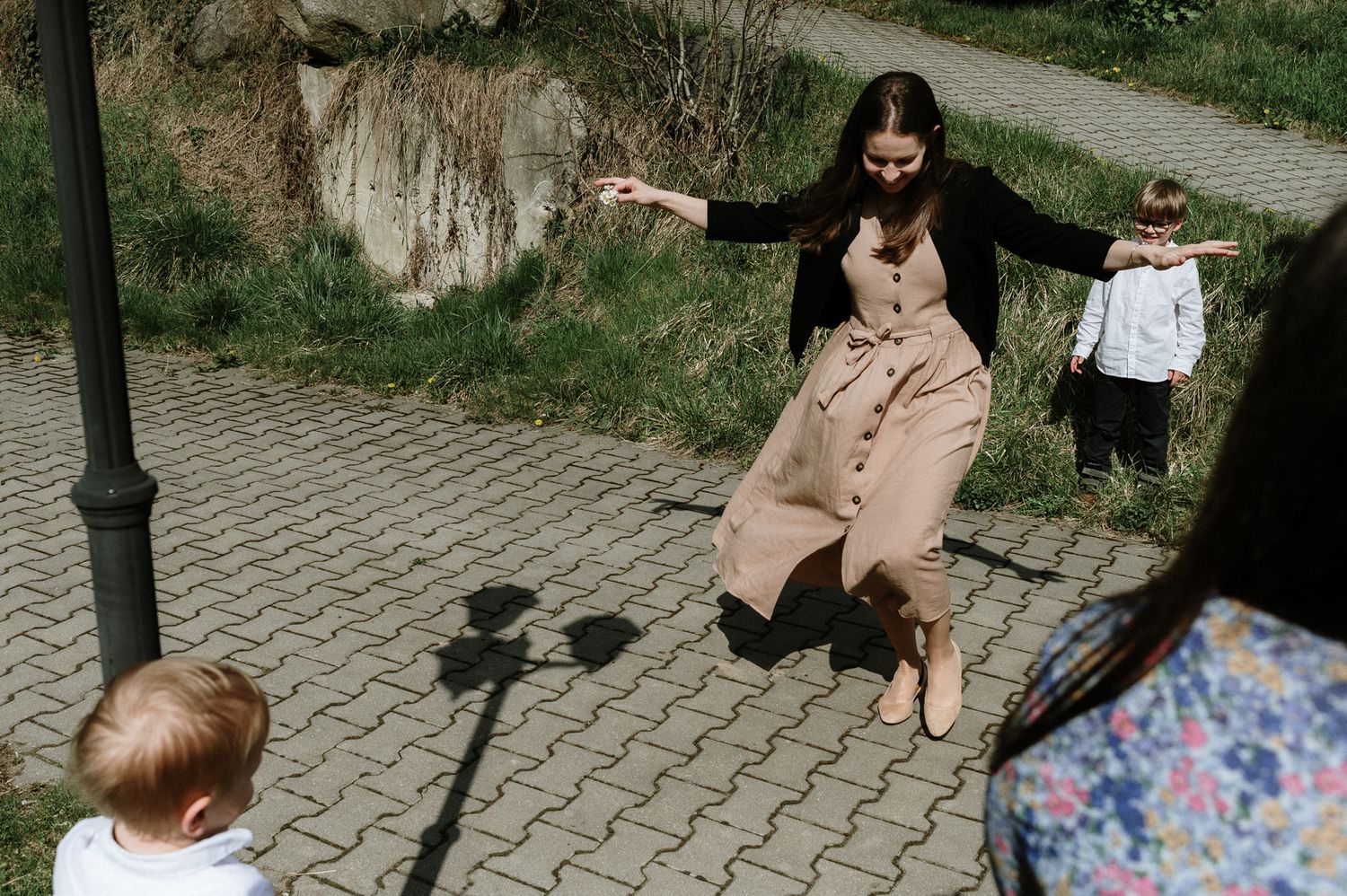 A group walks along a cobblestone path in a park on a sunny day.