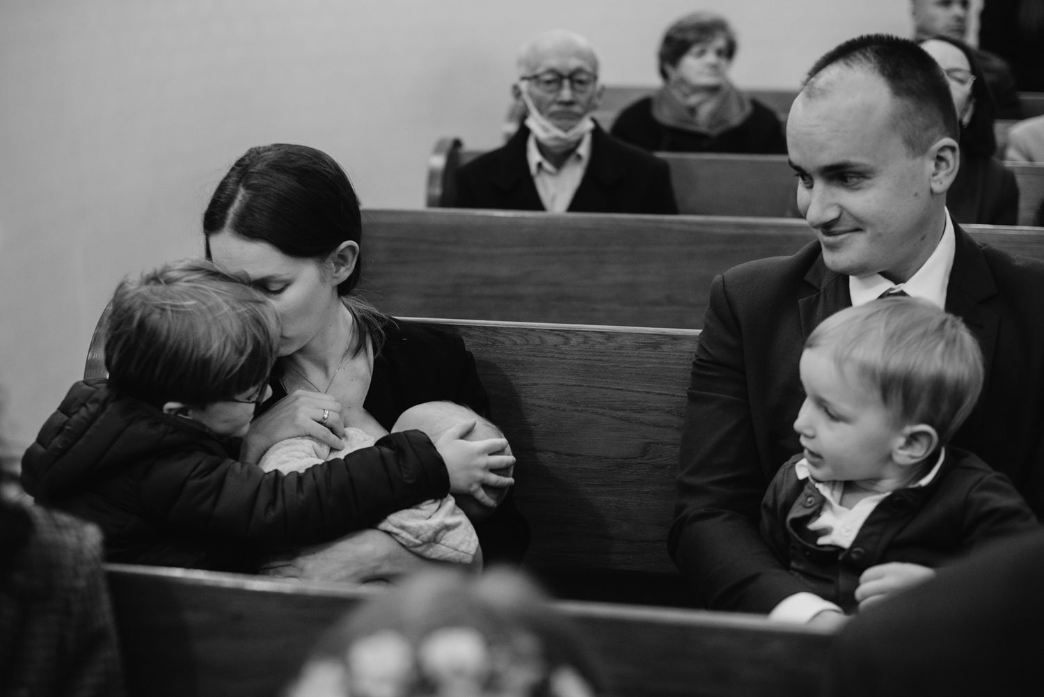 Wedding guests seated in wooden church pews during ceremony.