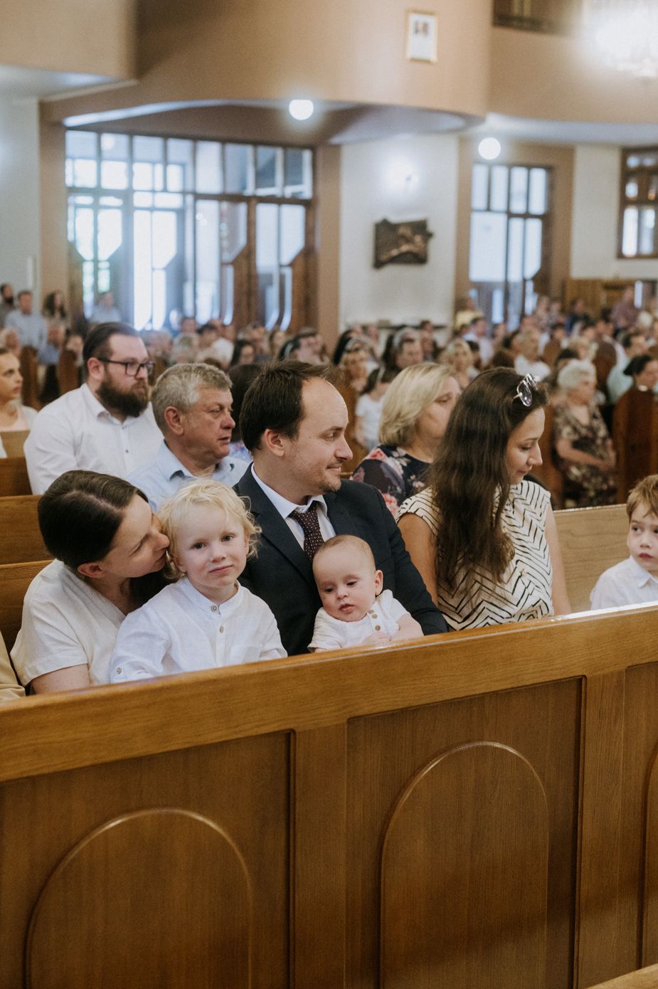 Congregation members sit together in wooden pews during a church service.