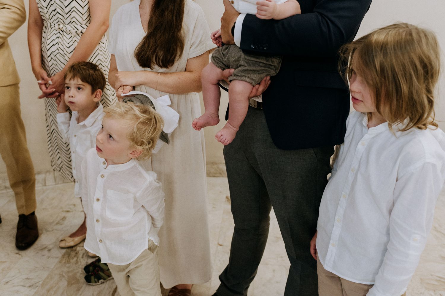A group of young children in white outfits dance together during a celebration event.