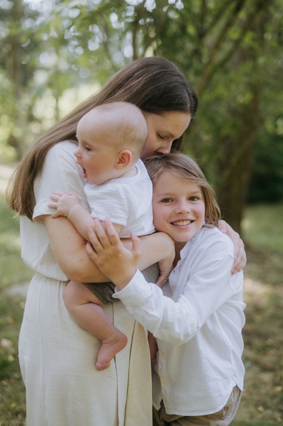 A sequence of outdoor family portraits showing sweet embraces between parent and child in white clothing.