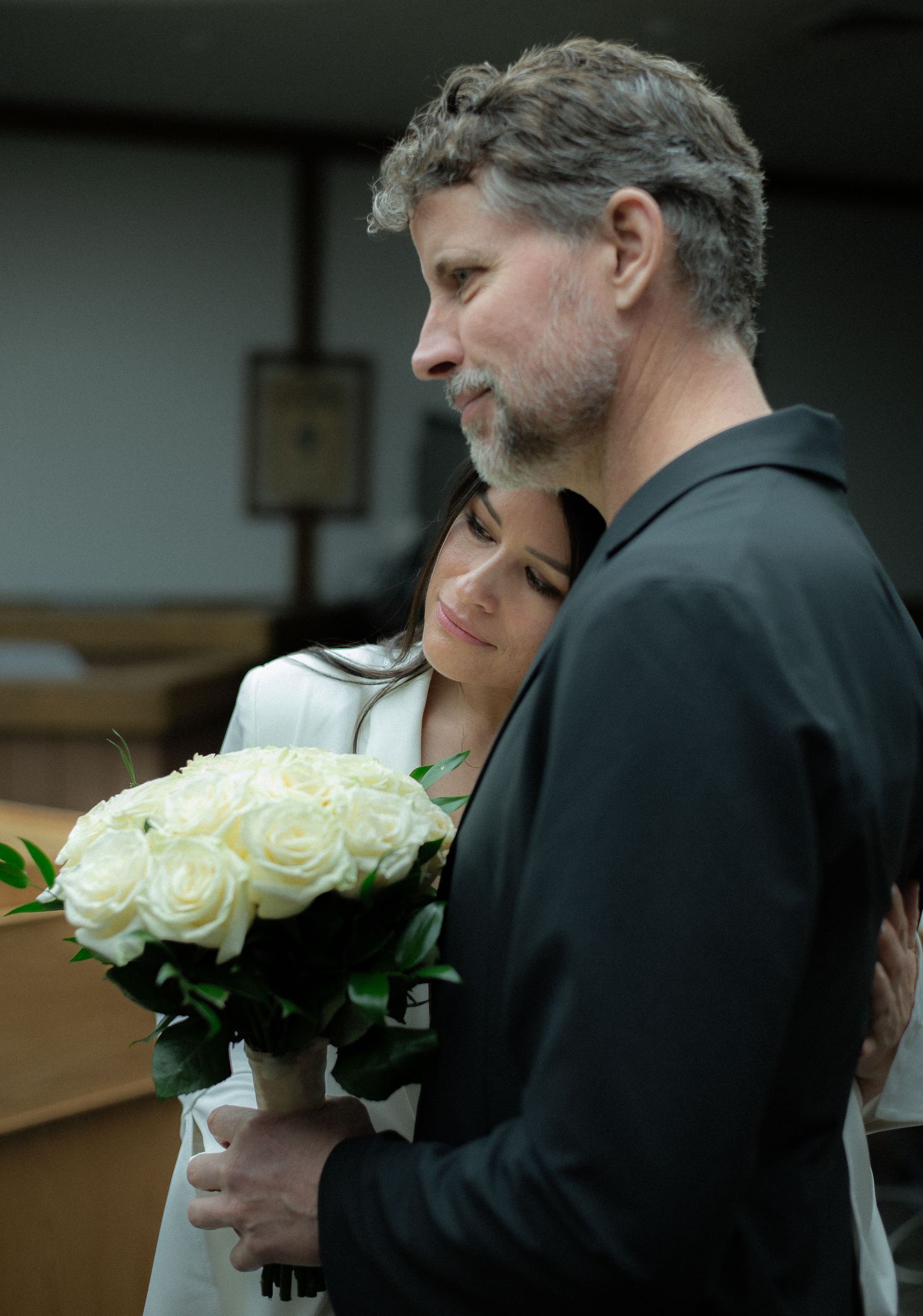 A bride rests her head on her groom's shoulder during their elopement wedding at the historic Blaine County Courthouse in Hailey, Idaho.