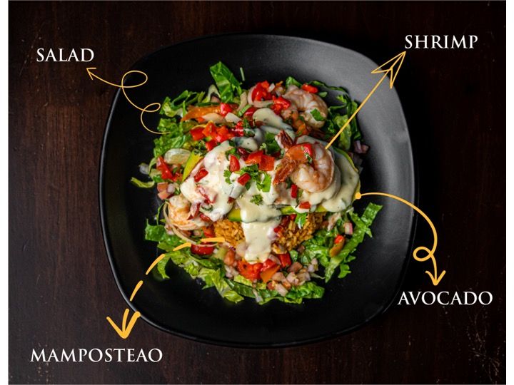 Fresh seafood salads with shrimp, avocado, and greens plated on black dishes with decorative garnishes.