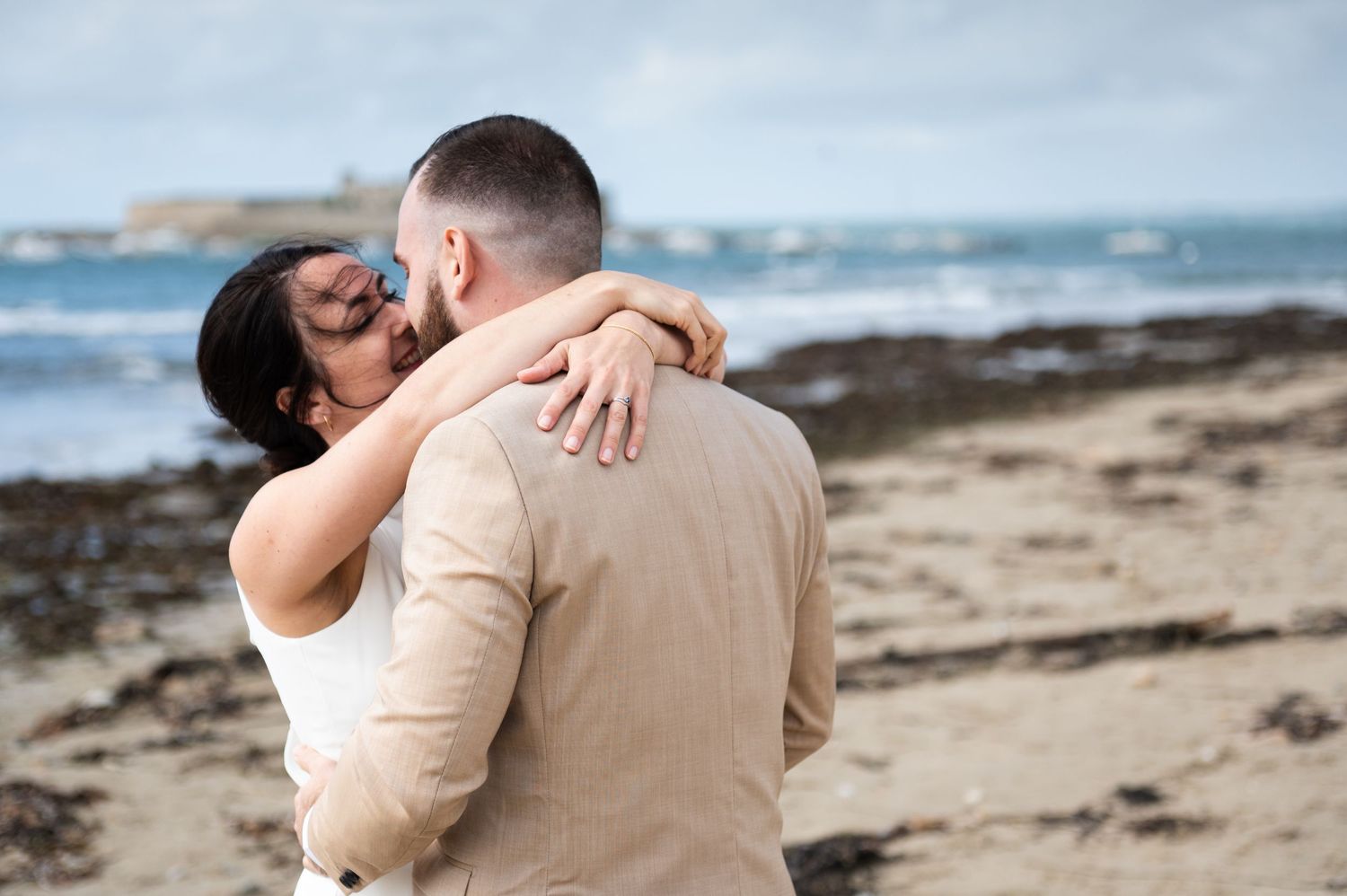 Couple de mariés enlacé sur une plage bretonne, séance photo mariage bord de mer.