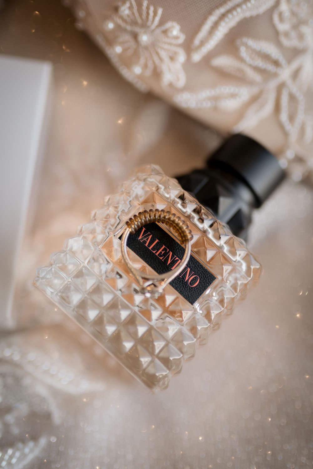 Artistic macro shots of a Valentino perfume bottle with crystal-like texture and reflective surfaces in soft beige lighting.