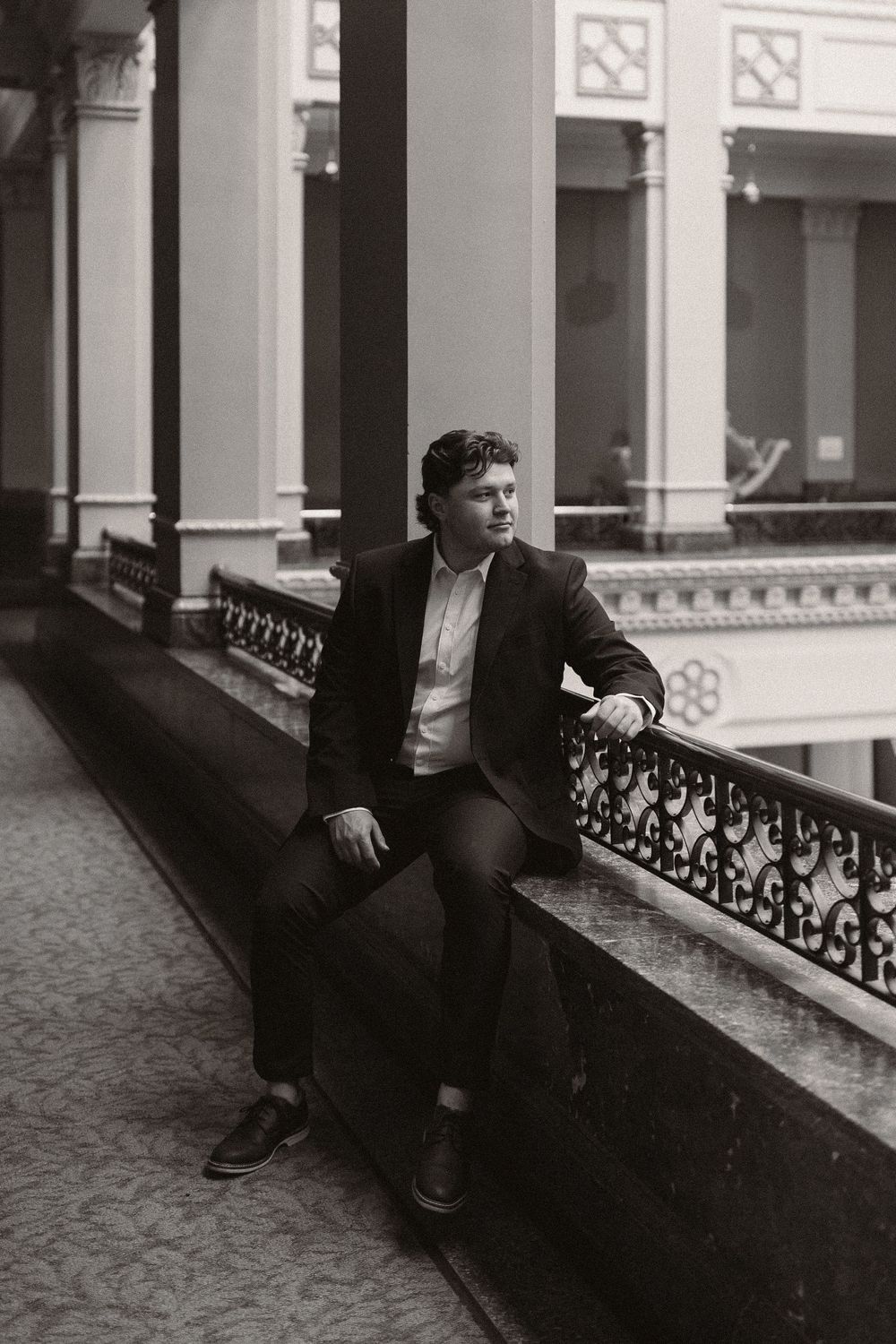 Black and white sequence showing a figure sliding along a railing in an elegant historic hallway.