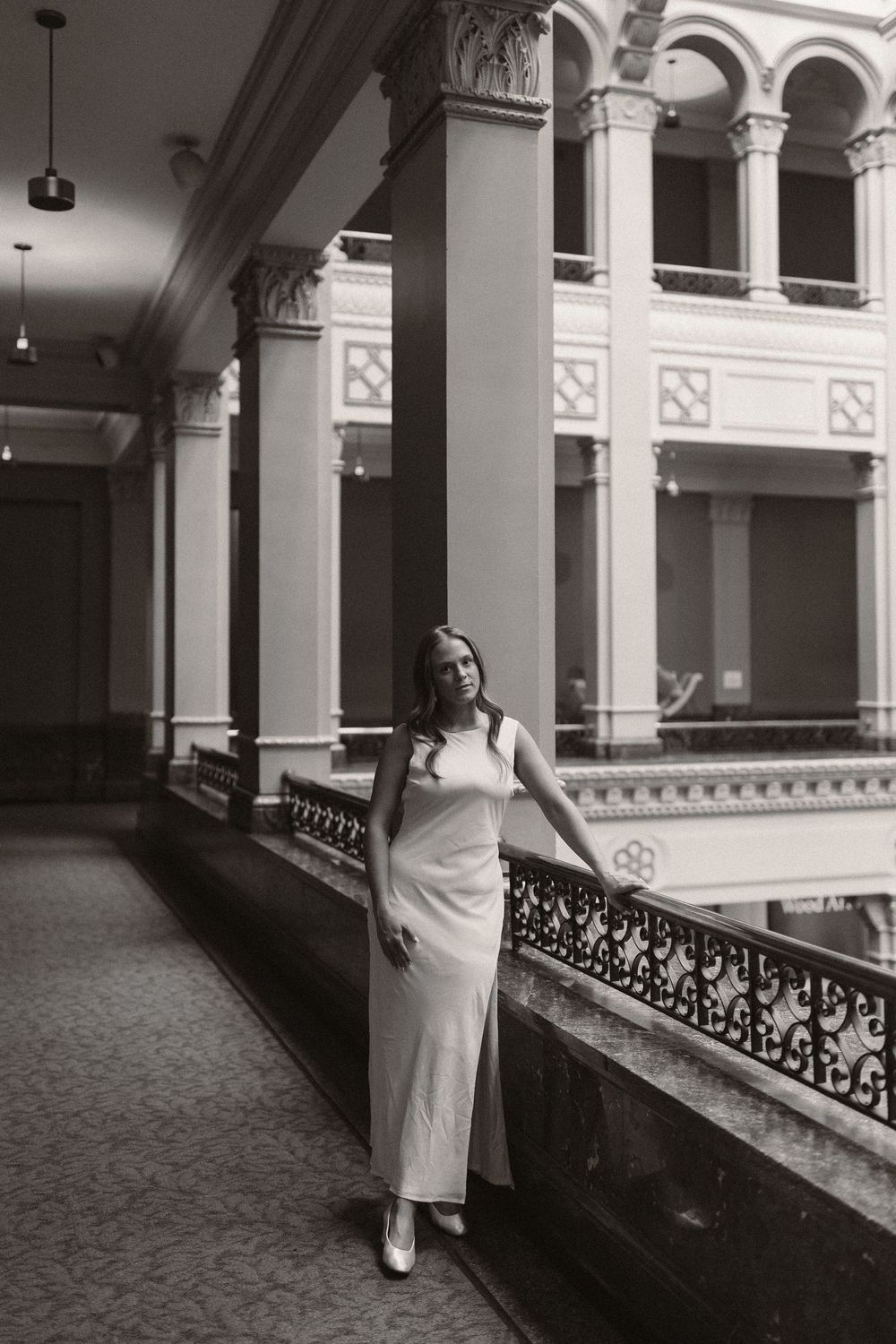 A sequence of black and white photos showing a person in white walking through an ornate corridor with classical columns.