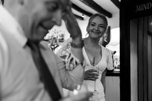Black and white candid wedding reception photos showing guests laughing and celebrating together at a festive event.