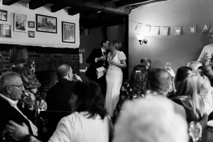 A crowded bar scene shows people gathered together in a dimly lit space with photos on the wall.