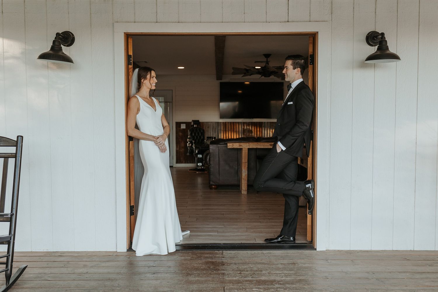 A couple in wedding attire stands in a rustic barn building with white shiplap walls at Lake Oak Meadows in Temecula.