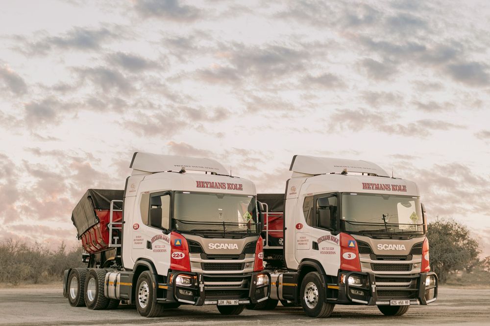 Two Scania Bothauns Bulk heavy-duty trucks parked side by side under a dramatic cloudy sunset sky.
