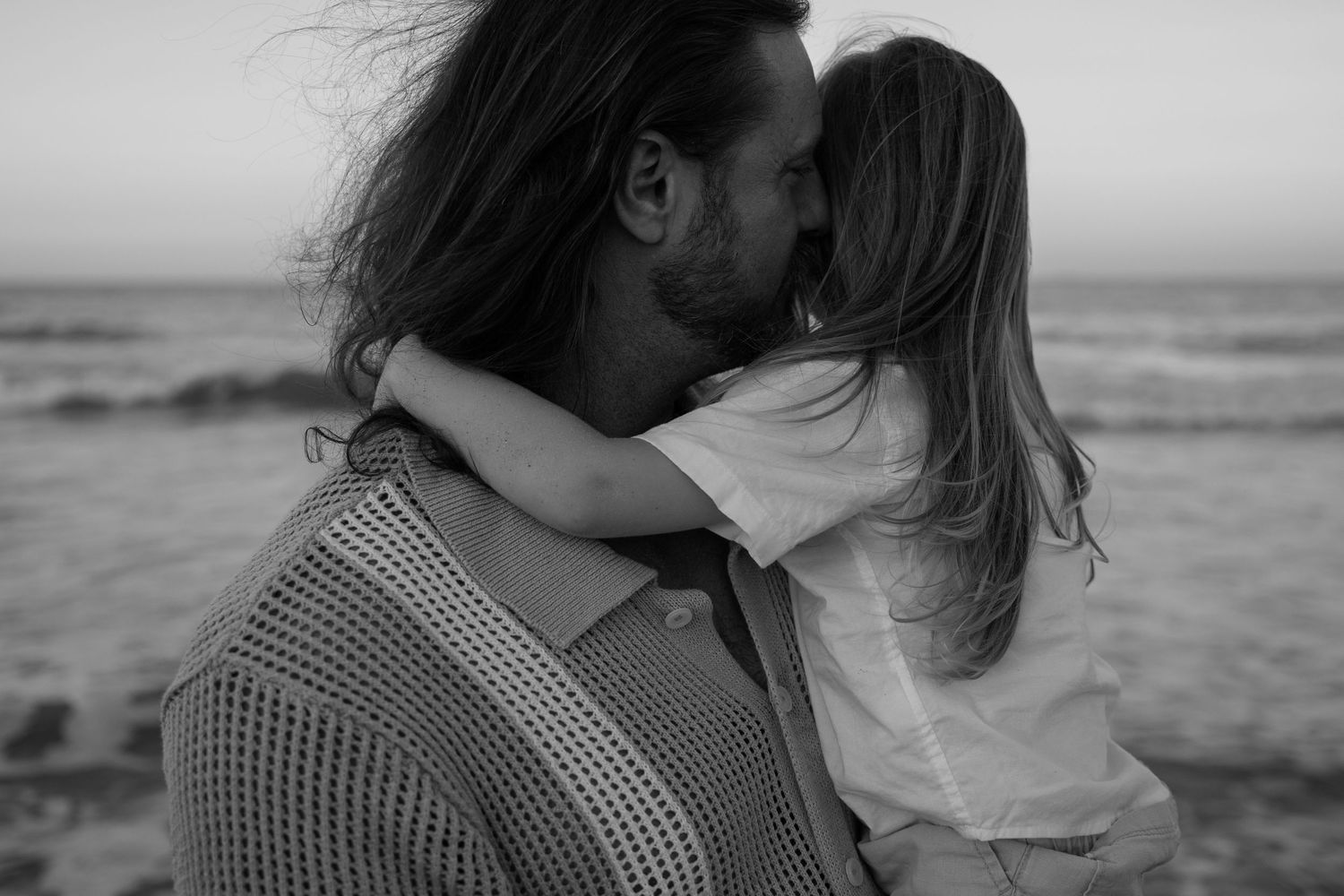Intimate black and white portraits of couple sharing tender moments by the ocean.