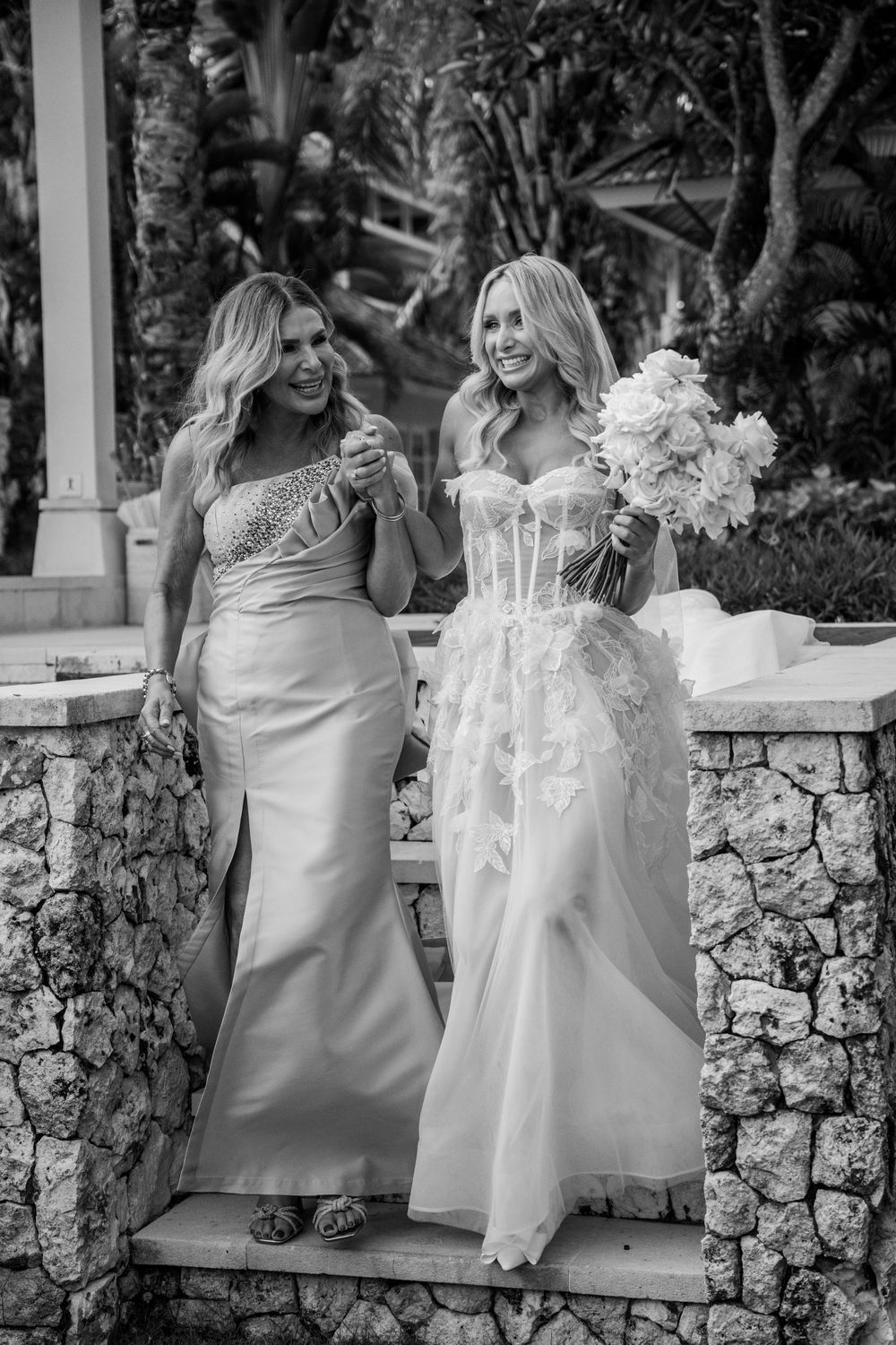 Series of black and white photos showing wedding guests sitting on white stone wall while sharing joyful moments together.