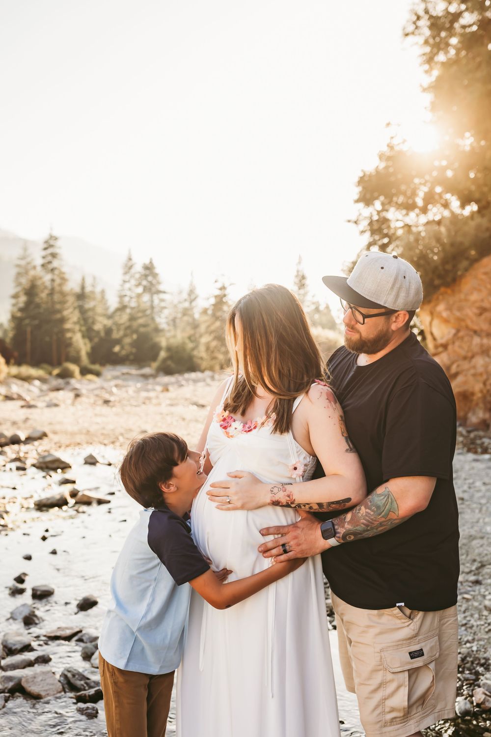 A family shares tender moments during a golden hour sunset photoshoot in a rocky outdoor setting.