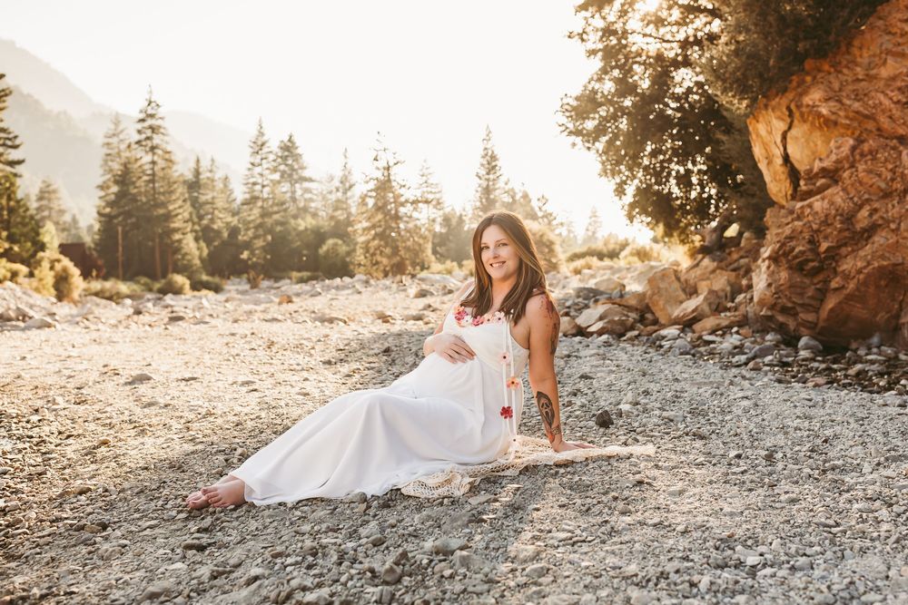 A white dress on a rocky outdoor ground during golden hour with evergreen trees and mountainous terrain in the background.