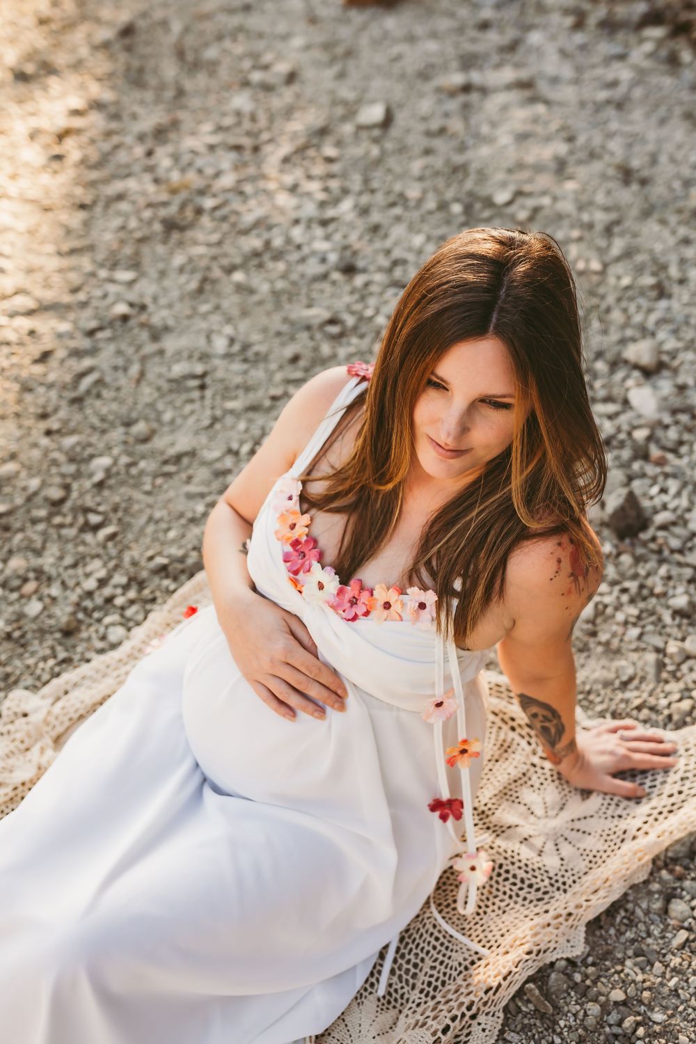 A figure in a flowing white dress reclines on a lace shawl in a series of dreamy outdoor poses.