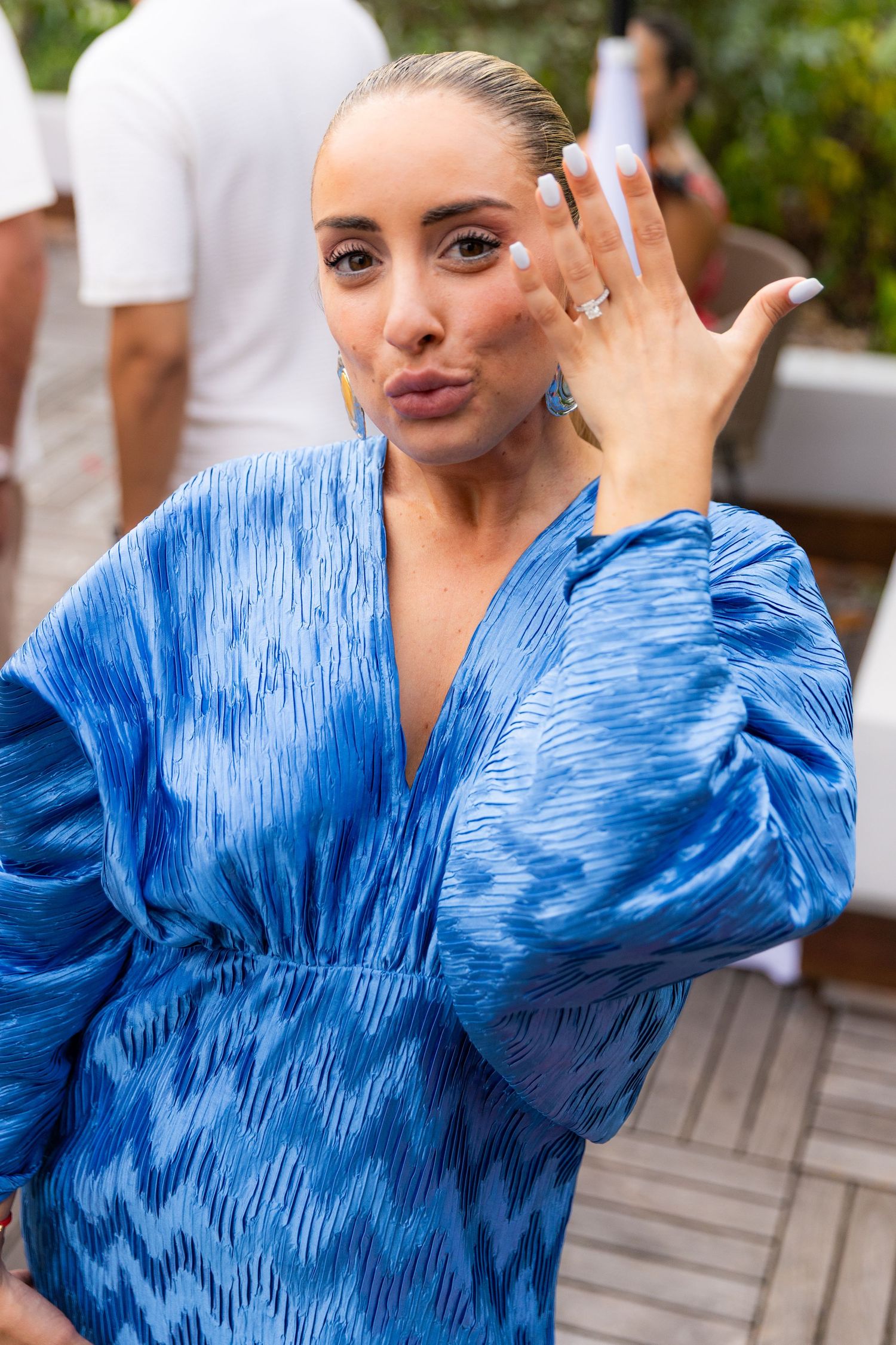Person in a bright blue patterned dress showing excitement during a special moment.