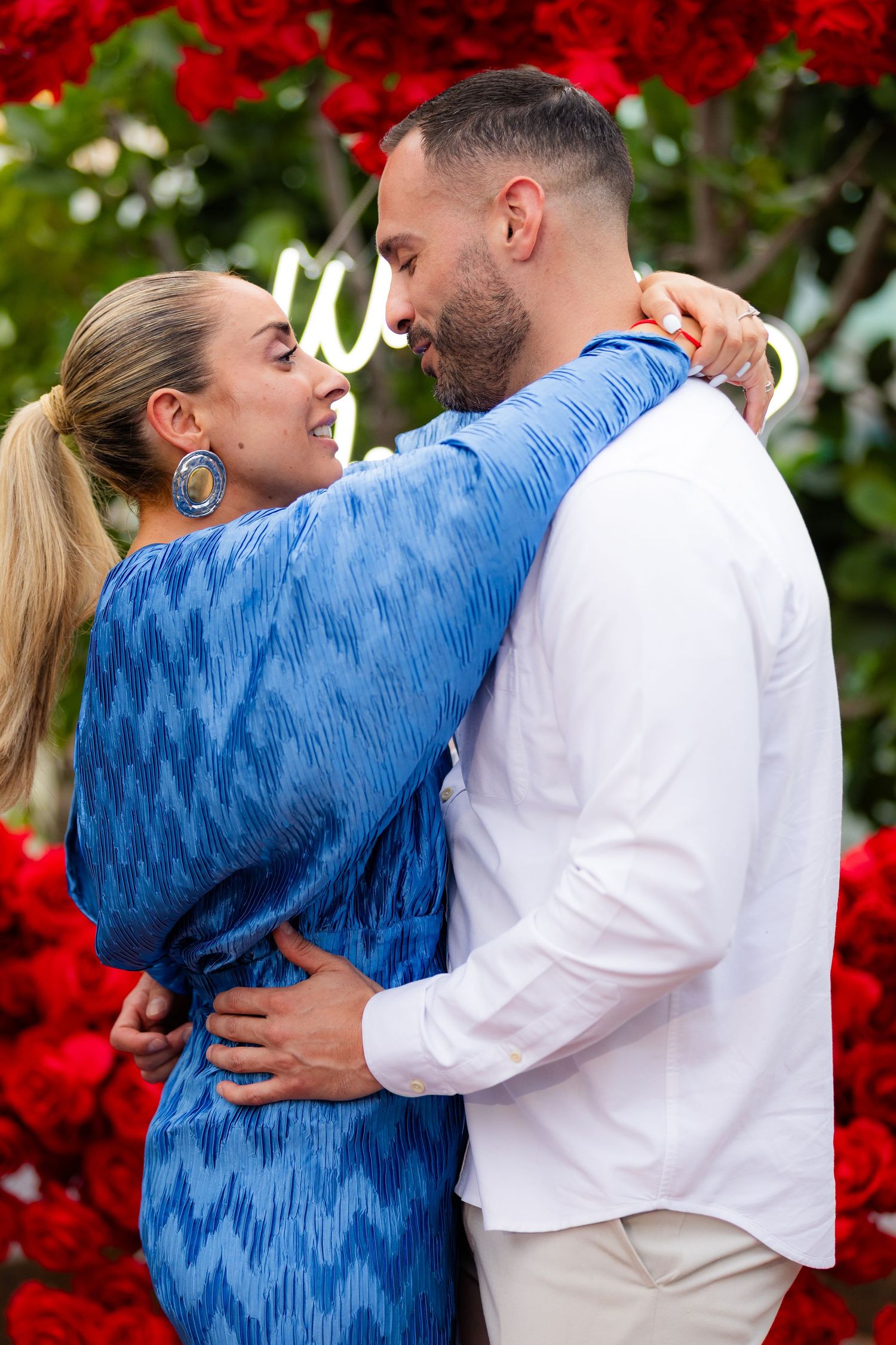 A sequence of romantic photos showing a couple embracing in front of red poinsettia flowers and greenery outdoors.