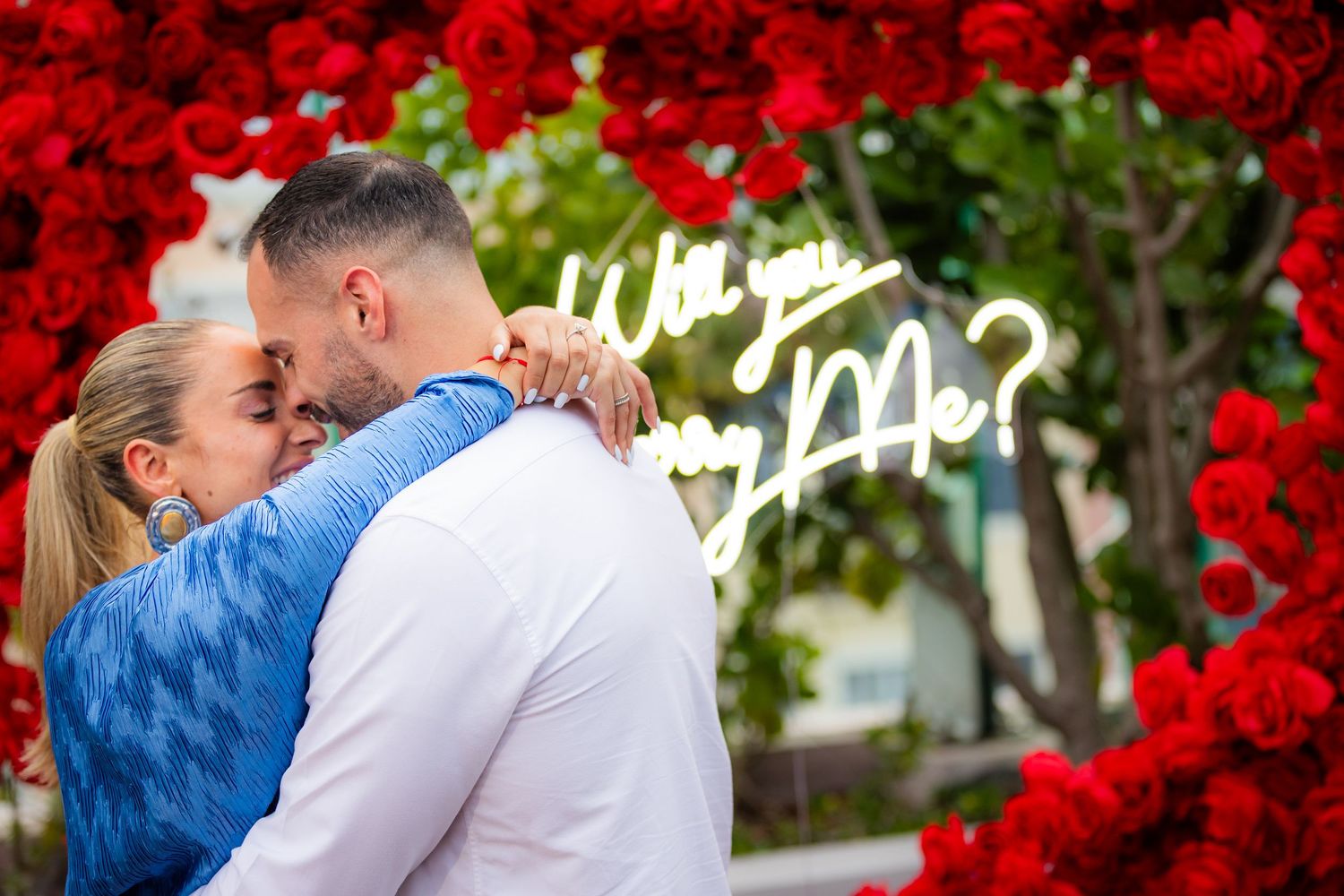 Red rose arch with candles creates romantic ambiance during an outdoor evening celebration.