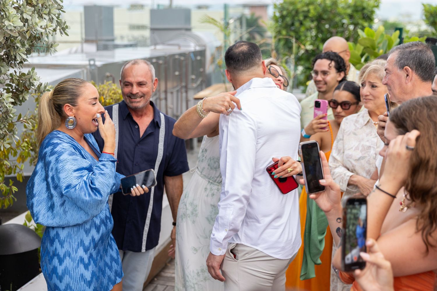A group of wedding guests enjoying themselves at an outdoor celebration with laughter and joyful expressions.