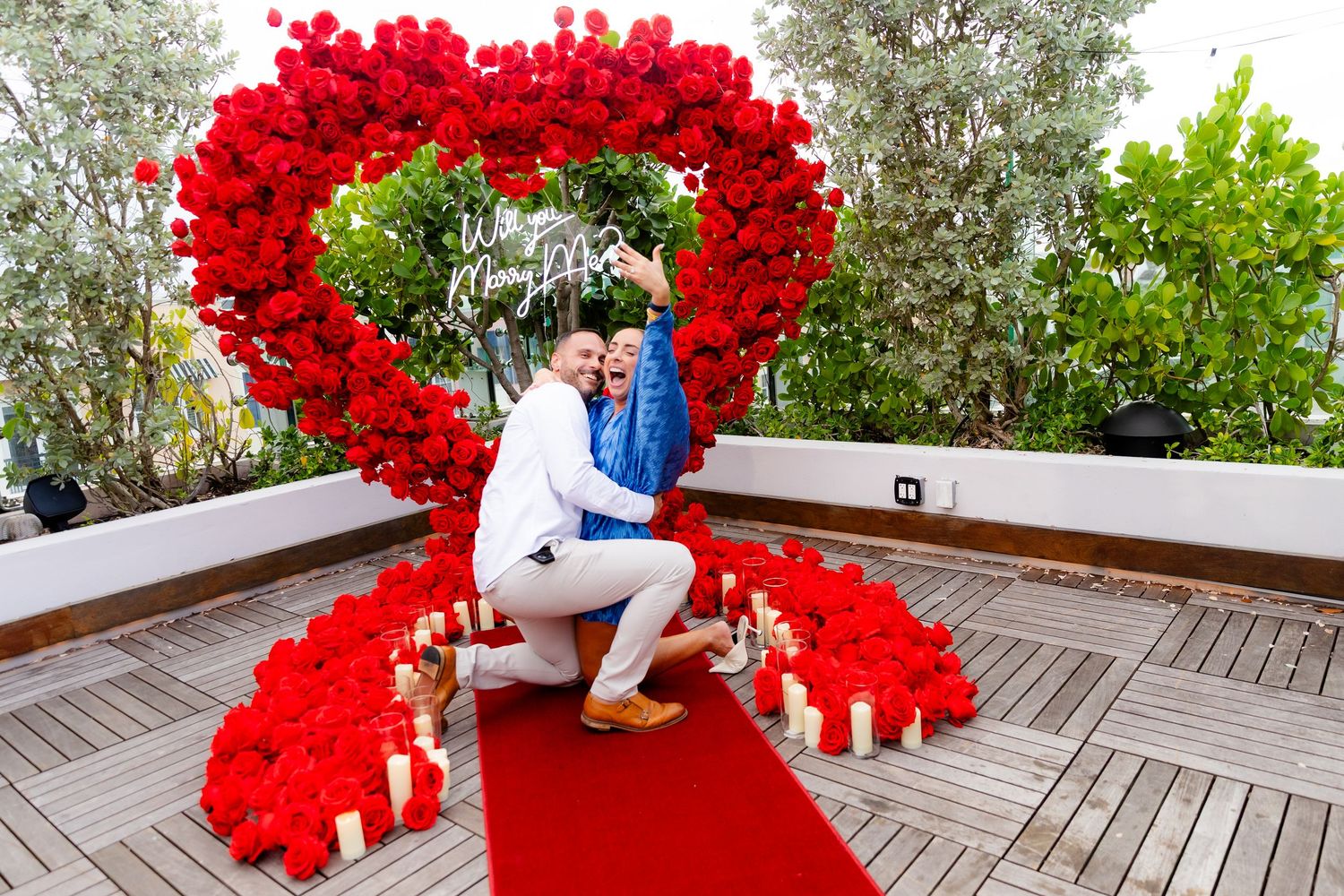 A beautiful heart-shaped balloon installation in bright red creates a romantic setting on a wooden patio.